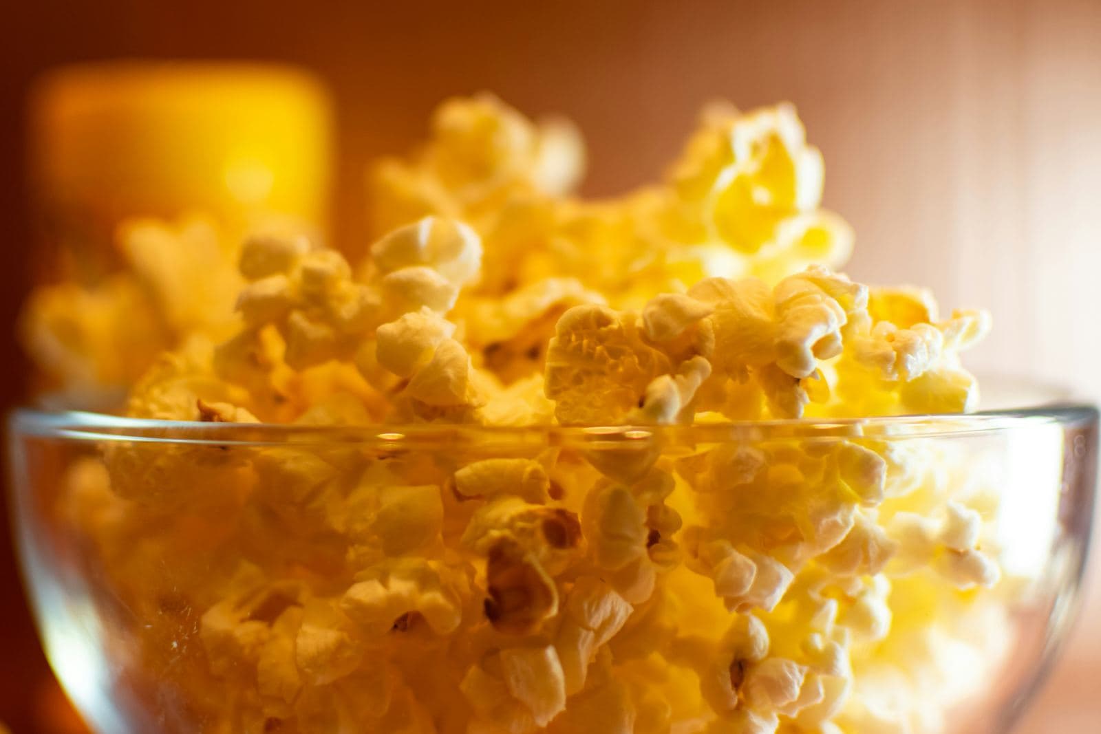 Glass bowl of golden popcorn in warm light